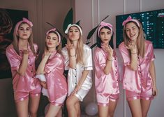 four women in pink pajamas posing for a photo together with their hands on their mouths