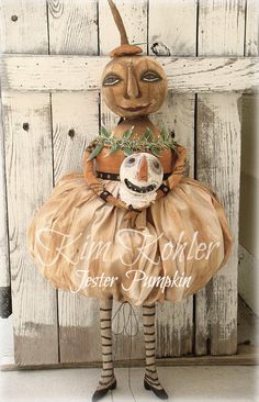 a scarecrow doll is standing in front of a wooden wall with the words pumpkin on it