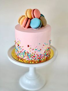 a pink cake with sprinkles and macaroons on top