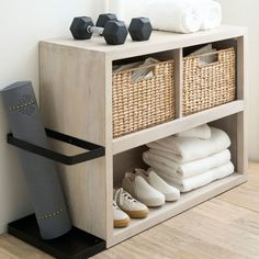 a wooden shelf with baskets, towels and shoes on it next to a white wall