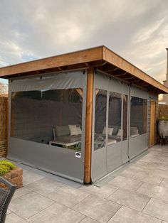 a covered patio area with chairs and tables on the outside, in front of a house