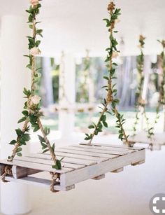 two wooden swings with flowers and greenery hanging from the ceiling in an empty room