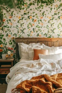 an unmade bed with flowers on the wall behind it