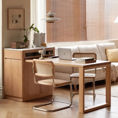 a living room with a couch, table and chair next to a window covered in blinds