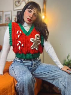 a woman sitting on top of a bed wearing a christmas sweater with gingerbreads