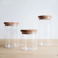 three glass jars with wooden lids on a table