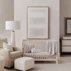 a baby's room with a crib, chair and ottoman