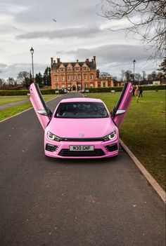 a pink car with its doors open on the road