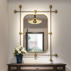 a vase with flowers sitting on top of a wooden dresser in front of a mirror