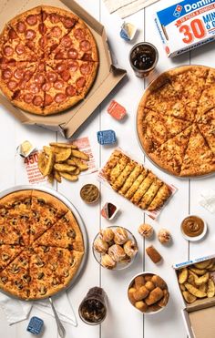 two pizzas and some snacks on a table