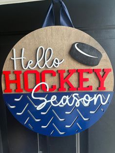 a wooden sign that says hello hockey season hanging on a door with a blue ribbon