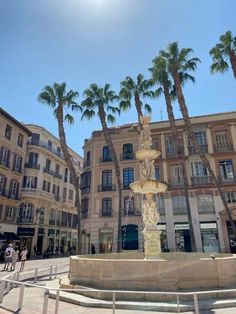 a fountain in the middle of a plaza with palm trees