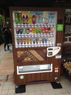 a vending machine sitting on the side of a road next to a wooden bench