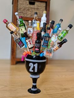 a black vase filled with liquor bottles on top of a wooden table