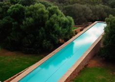 an aerial view of a swimming pool surrounded by trees and grass in the foreground