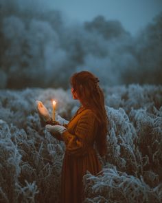 a woman in a field holding a candle