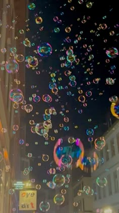 many soap bubbles are floating in the air on a city street at night time,