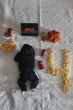 a baby laying on top of a bed next to the word netflix spelled out with popcorn