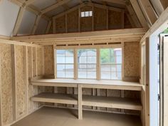 an empty room with shelves and windows in the middle, surrounded by plywood boards