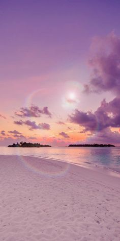 the sun is setting over an empty beach