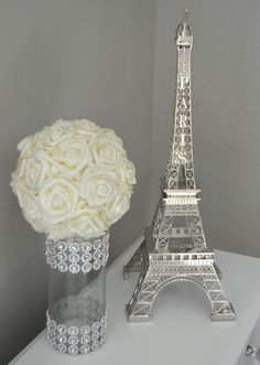 there is a vase with roses in it next to the eiffel tower statue