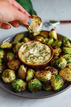 a plate full of brussel sprouts with a dipping sauce in the middle