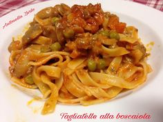 a white plate topped with pasta and meat covered in sauce on top of a red checkered table cloth