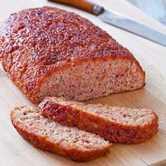 sliced meatloaf sitting on top of a cutting board next to a knife