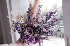 a vase filled with purple flowers sitting on top of a window sill