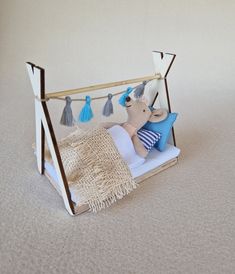 a teddy bear sitting on top of a bed with tassels hanging from it's sides