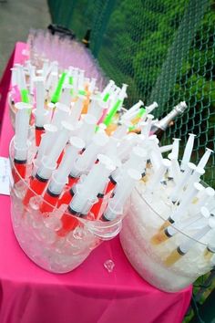 there are many different types of toothbrushes in cups on the table with pink cloth