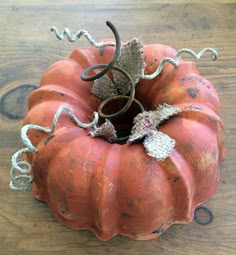 an orange pumpkin sitting on top of a wooden table next to a metal wire sculpture