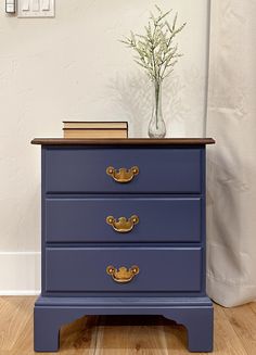 a blue dresser with two drawers and a book on top, in front of a white wall