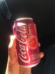 a person holding up a can of cherry soda