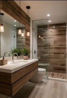 a modern bathroom with wood paneling and glass shower door, white countertop sink and toilet