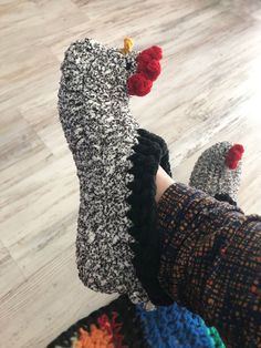 someone's feet wearing knitted slippers with pom poms