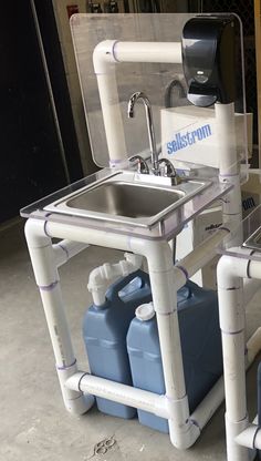 a sink with two water tanks attached to it and some pipes on the wall behind it