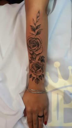 a woman's arm with a rose tattoo on her left arm and the other hand