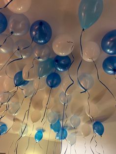 blue and white balloons are hanging from the ceiling