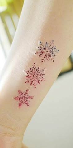 a snowflake tattoo on the left wrist and right arm, with red ink