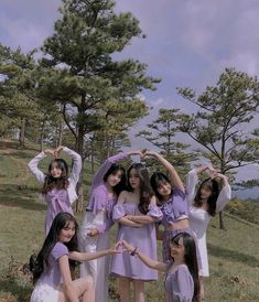 a group of young women standing next to each other on top of a grass covered field