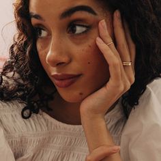 a woman with freckled hair is holding her hand to her face and looking at the camera