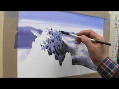 a man is painting a mountain scene with watercolors