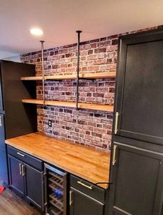 a kitchen with brick wall and wooden counter tops, black cabinets, and wine racks