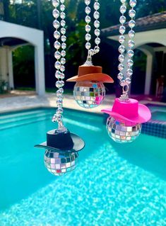 three disco balls hanging from the ceiling next to a pool with a cowboy hat on it