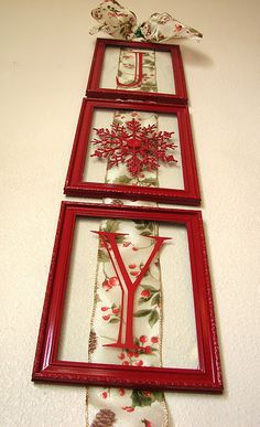 three red frames are hanging on the wall, each with a christmas tree and two birds