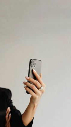 a woman is holding up her cell phone to take a selfie with her hand