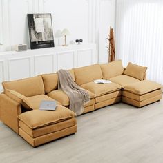 a living room with white walls and wood flooring has a sectional couch in the middle