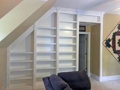 a living room filled with furniture and bookshelves next to a stair case door