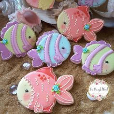 decorated cookies are displayed on a table with flowers and seashells in the background